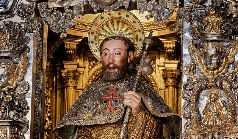 Imagem do apóstolo Santiago com auréola, manto bordado com a cruz de Santiago e bordão de peregrino, no altar-mor prateado da Catedral de Santiago de Compostela