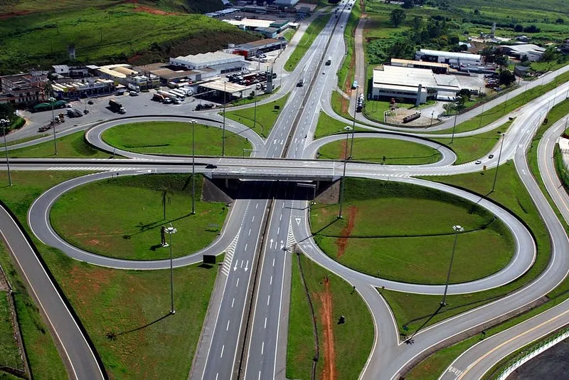 Vista aérea de um trevo de vários níveis na Rodovia Fernão Dias, com viaduto e alças curvas que separam os fluxos de veículos